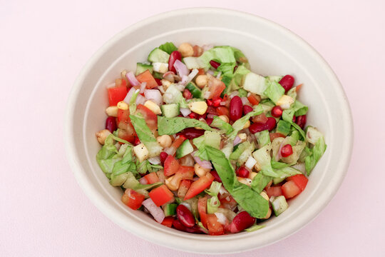 Fresh Healthy Mixed Vegetable Salad with Chickpeas, Kidney Beans, Corn and Pomegranate in White Bowl. Perfect for healthy eating, vegan and vegetarian diets, food blogs, and lifestyle concepts.