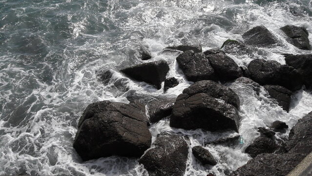 Ocean waves crashing against dark coastal rocks with white foam
