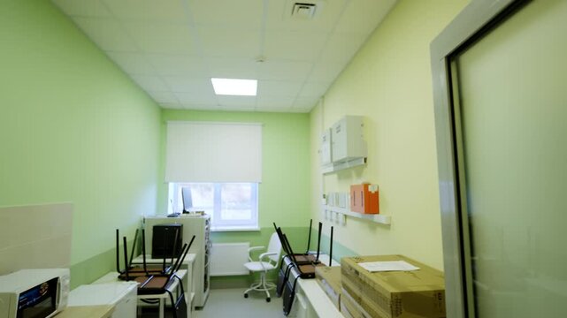 Staff room in modern clinic features tables chairs and microwave oven. Comfortable place for relaxation. Countertops for preparing meals