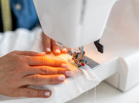Craftsperson stitches white fabric on sewing machine