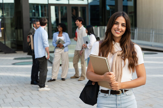 Student girl smiling at camera standing in front University building on campus at college