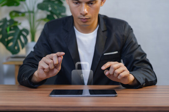 Young Man in Formal Suit Using Tablet at Desk with Green Plant Background
