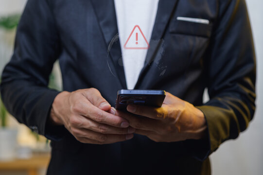 Businessman Holding Smartphone with Warning Alert on Screen in Modern Office