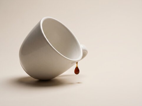 White ceramic coffee mug tipped over dripping single drop