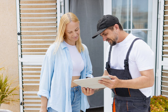 Service worker and homeowner discussing a digital contract through a tablet, considering agreement terms for repair and delivery, confirming professional assistance