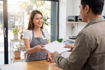 Fototapeta premium Retail Associate Providing Paper File To Customer At Service Desk