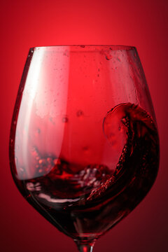 Wine glass with red liquid frozen in movement.