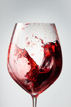 Wine glass with red liquid frozen in movement.