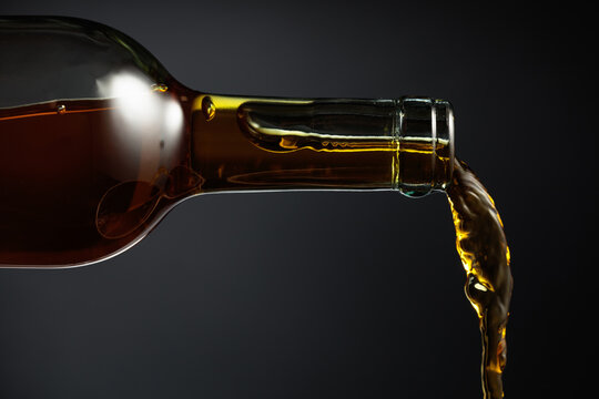 White wine of a rich amber color pours out of the bottle.