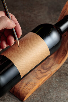 Man writes with a pencil on a blank label.