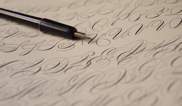 Calligraphy pen resting on parchment paper with elegant cursive script, document