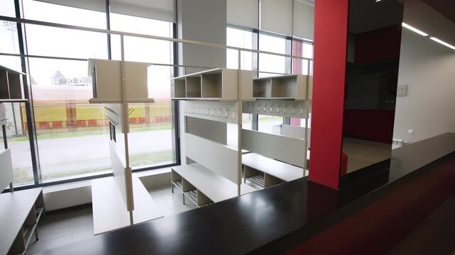 Interior displays tidy wardrobe racks equipped with metal clothing hooks and benches. Bright daylight fills spacious minimalist room