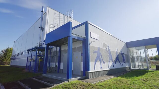 Modern sports facility building with solid bright blue framing. Table tennis silhouettes decorate facade promoting spirit of sportsmanship