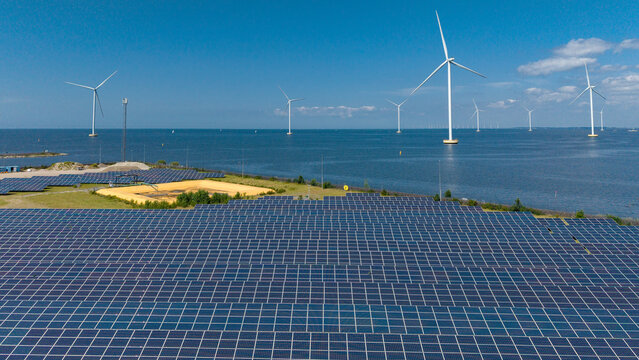 Aerial view of the Maxima Power Plant featuring rows of solar panels and industrial chimneys on the coast of the Markermeer in Lelystad, Flevoland, The Netherlands.