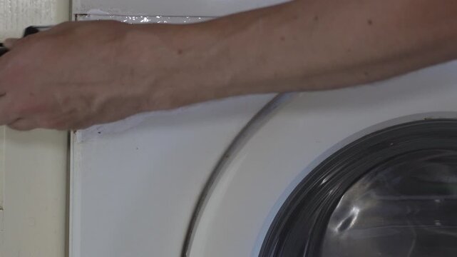 Painting washing machine front panel with brush, Handyman restoration of home appliance by painting front panel with brush