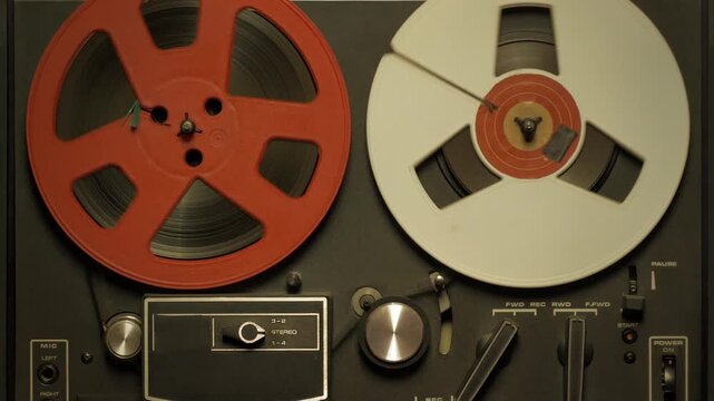 Vintage reel-to-reel tape recorder playing magnetic audio tape. Music production and entertainment, close up background video loop