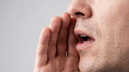 Fototapeta premium Close-up of Man Whispering a Secret or Shouting with Hand Near Mouth, Male Profile Telling Rumor or Making Announcement, Communication Concept