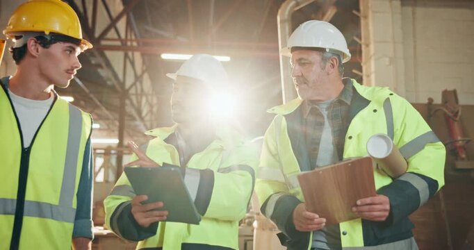 Team, tablet and clipboard in factory with talking, blueprint or tools for construction project flare. Manager, task delegation or online floor plan with men for maintenance or remodel partnership