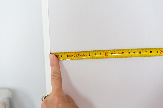 Person measuring a white door frame with a yellow tape measure