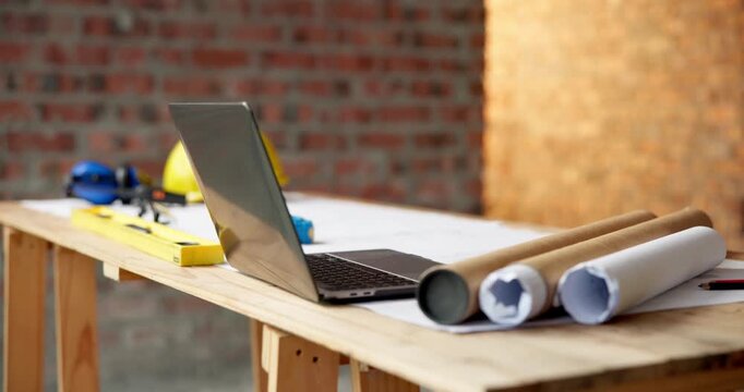 Architecture, laptop and blueprint at empty site for building, maintenance or property development. Computer, floor plan and equipment on desk by construction design for repairs or renovation.