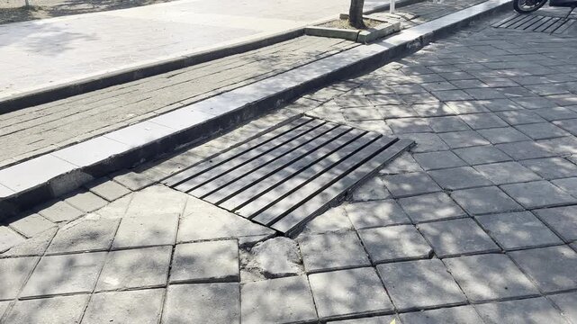 Metal drainage grate on outdoor public pedestrian paving