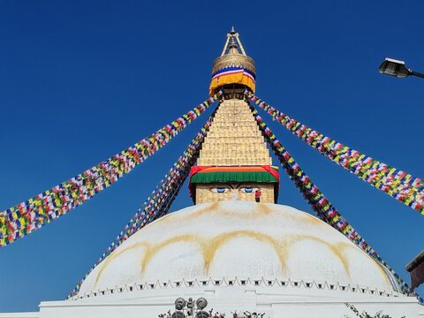 Nepals iconic Boudhanath Stupa with vibrant prayer flags against a clear blue sky