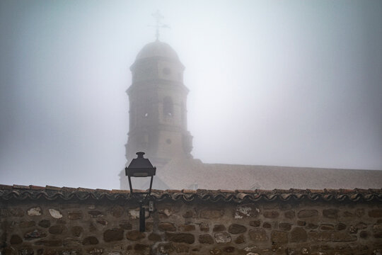 Historic street lamp with Baeza Cathedral in the fog, Andalusia, Spain