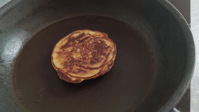 Gluten-free pancake being flipped with a spatula in a frying pan