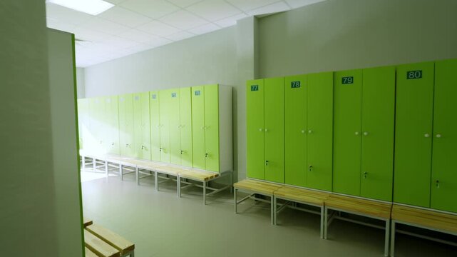 Lockers with numbers stand in empty changing room near wooden benches. Clean modern space offers quiet atmosphere before sports training