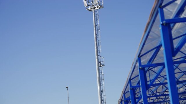 Floodlight mast with multi-LED panels stands against clear sky. Modern outdoor lighting system ensures excellent conditions for training
