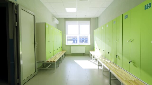 Clean locker room displays storage cabinets under large sunny window. Modern interior offers quiet environment before active workouts