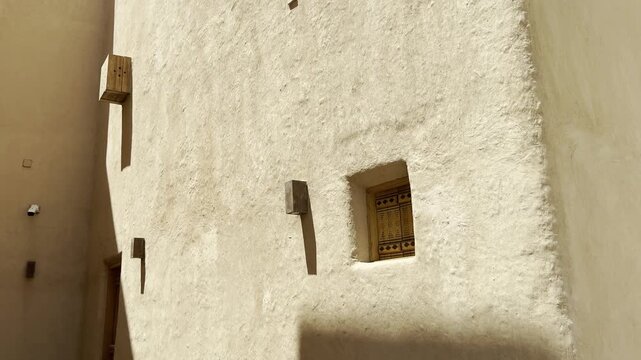 A small historic decorated wooden window on an ancient mud building wall in Riyadh