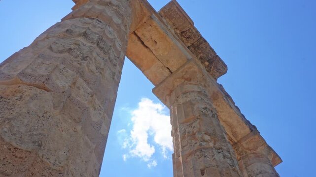 Young female tourist waving from ancient ruins of Zeus temple in Nemea, Greece