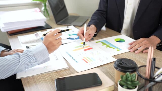 Business professionals reviewing financial reports and charts during a meeting, discussing performance, strategy, and business growth.