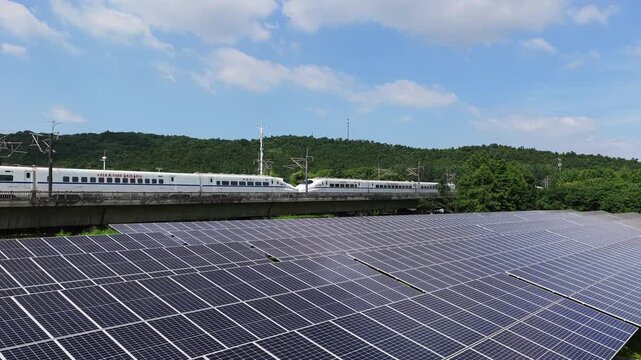 High-speed train passing solar power plant in rural landscape
