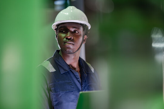 Professional factory engineer observing production equipment before maintenance using digital technology in industrial workplace. Machine diagnostics, industrial automation, manufacturing process.