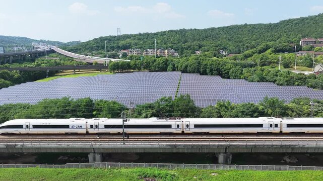 High-speed train traveling beside large solar panel farm