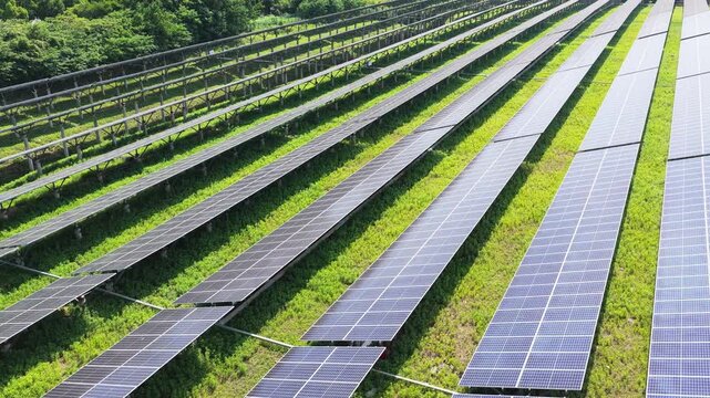 Aerial view of long photovoltaic panel rows over green field