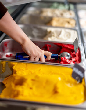 Hand scoops vibrant red ice cream at shop