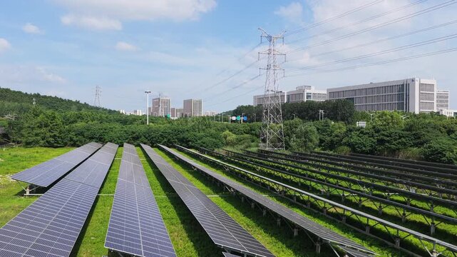 Aerial view of photovoltaic solar farm near city and transmission towers