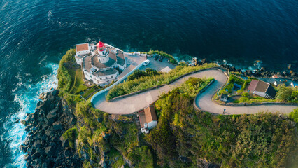 Farol do arnel lighthouse on a winding coastal road at dusk © Alberto