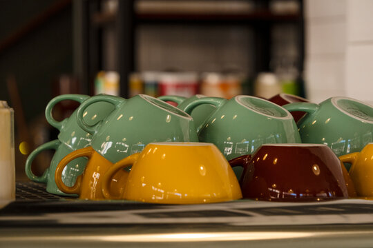 Colorful ceramic cups sit on a tray in a coffee shop.