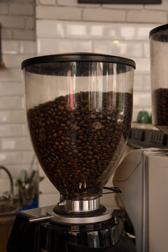 The coffee grinder in the coffee shop is filled with coffee beans.