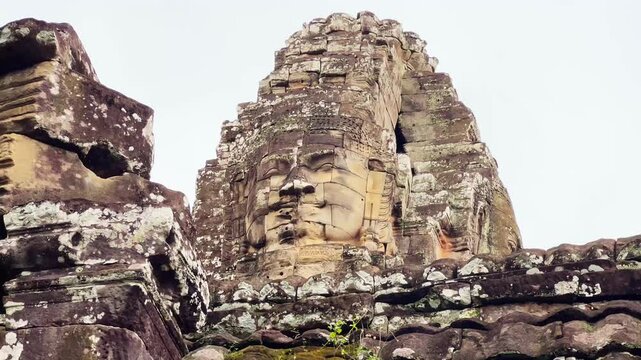 Close-up footage of the iconic smiling stone face tower at Bayon Temple in Angkor Thom, Siem Reap, Cambodia. The video captures the intricate Khmer architecture, weathered sandstone carvings, and the