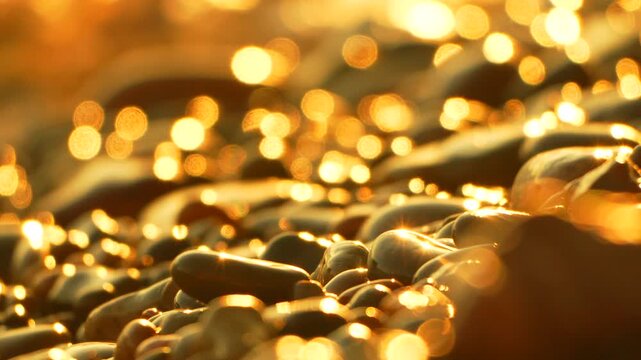 Pebbles beach golden abstract sparkling wet stones glistening in warm sunlight bokeh background