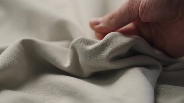 man manually check ivory color cotton fabric for clothing with hands
