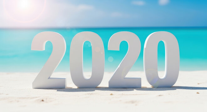 Large white three dimensional numbers forming year twenty twenty standing on sandy beach shore with blurred tropical blue sea background at sunset.