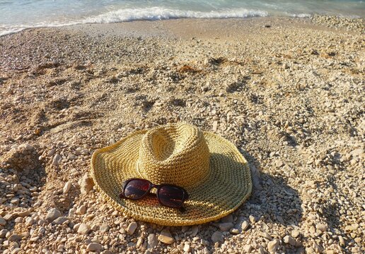 Woman straw hat with glass on the beach by the sea, summer accessories
