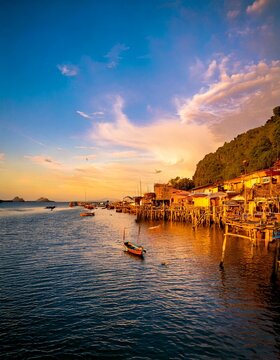 Traditional Stilt Houses and Fishing Boats Along Coastal Waterfront at Sunset