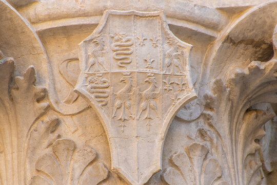 Detail of an antique column with the Symbols of Milan. Italian architecture. Details of Old Building Facade with Arched Elements and white marble Stone Corbels.
